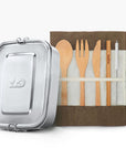 Silver lunch tin beside a roll up fabric pouch containing wooden cutlery.