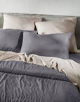 Gray bedding set with pillows on a bed against a white wall