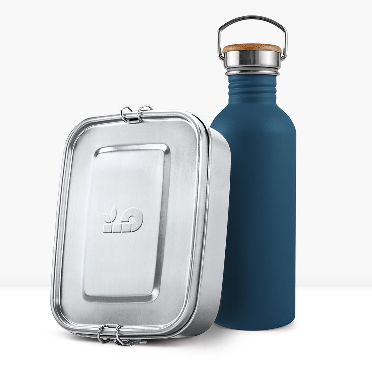 Navy blue non insulated bottle with a wooden lid and metal handle beside a metal lunch tin