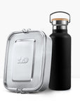 Close up of a silver metal lunch tin beside a matte black insulated bottle with a wooden cork lid
