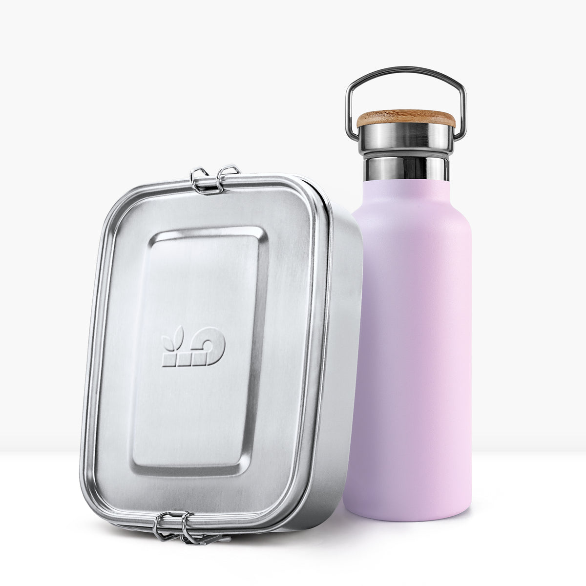 Close up of a lavender insulated bottle with a wooden cork lid beside a silver lunch tin