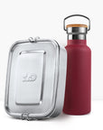 Close up of a red insulated bottle with a cork lid next to a silver lunch tin