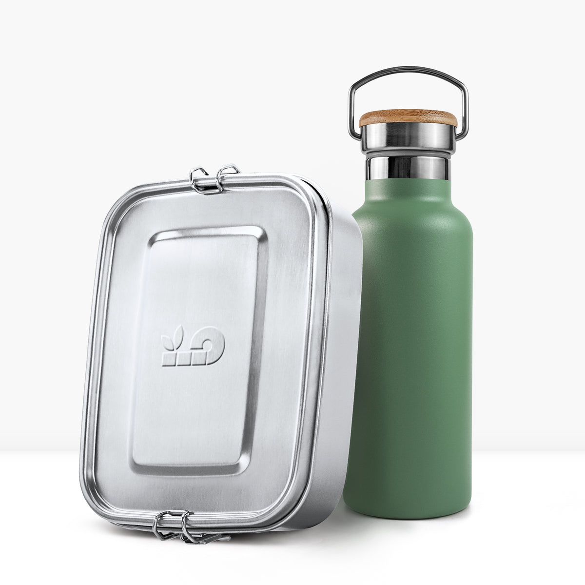Green insulated bottle with cork cap and metal handle beside a silver lunch tin.