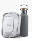 Grey insulated bottle with cork cap and metal handle beside a silver lunch tin.