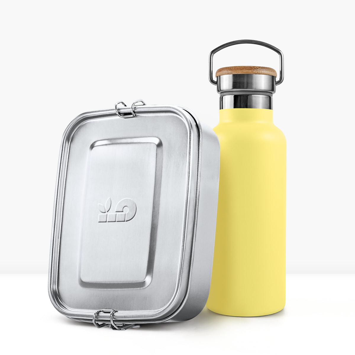 Yellow insulated bottle with cork cap and metal handle beside a silver lunch tin.