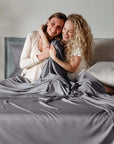 Two women hugging under bambaw cozy bamboo gray bedding on a bed.