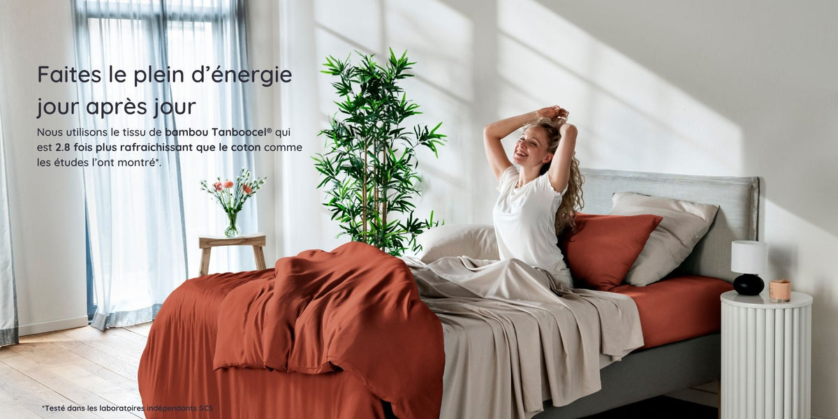 Woman waking up in a bright bedroom in a bed with bambaw cozy bamboo bedsheets in terraccota and sand colours with natural light and plants.