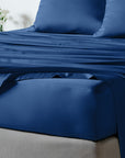 bambaw cozy bamboo bed sheets close up on a bed with fitted sheets and pillows in navy blue colour