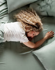 Woman sleeping on a bed with light green bamboo bedding