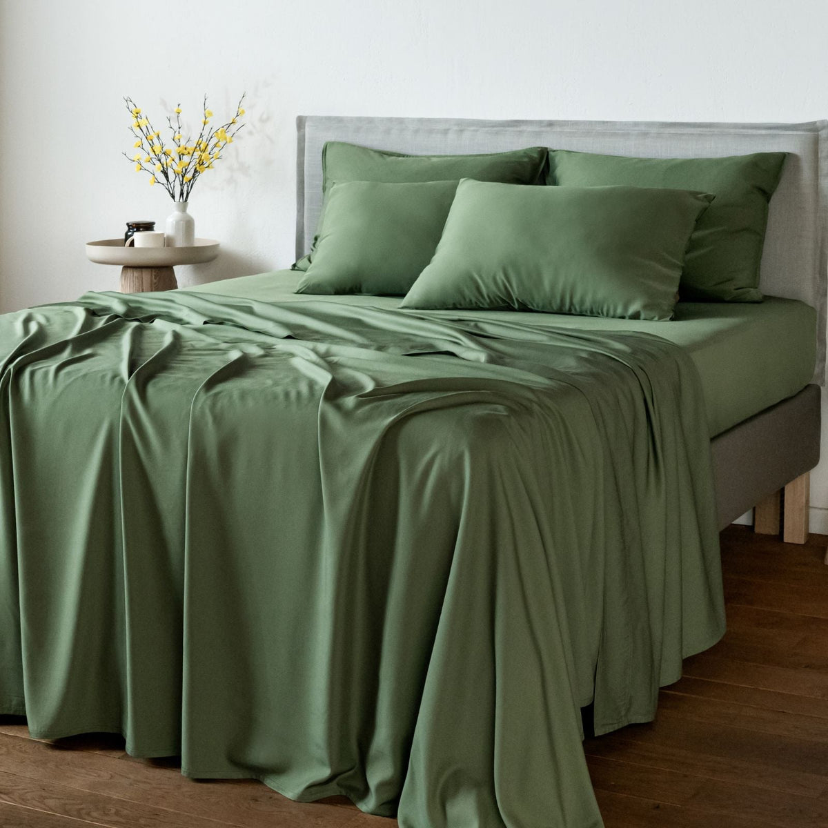 Bambaw Cozy bamboo flat sheet, fitted sheet and pillowcases in olive green colour on a bed in a bright room