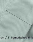 Close-up of light green bamboo fabric with a hemstitched finish and measurement text.