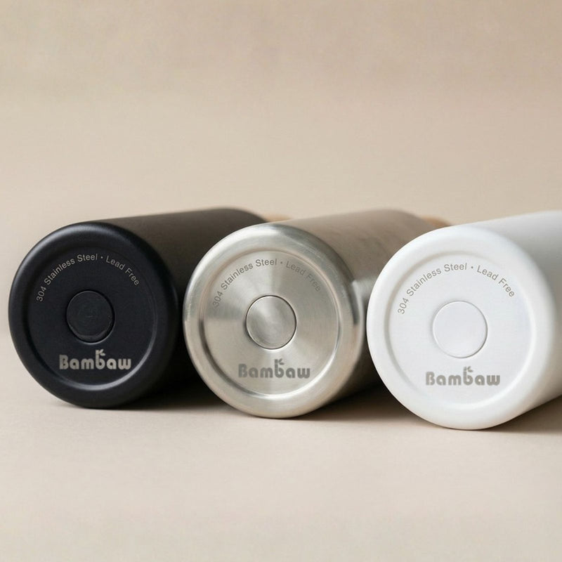 Three Bambaw stainless steel bottles in black, silver, and white with 'Bambaw' branding on a beige background.