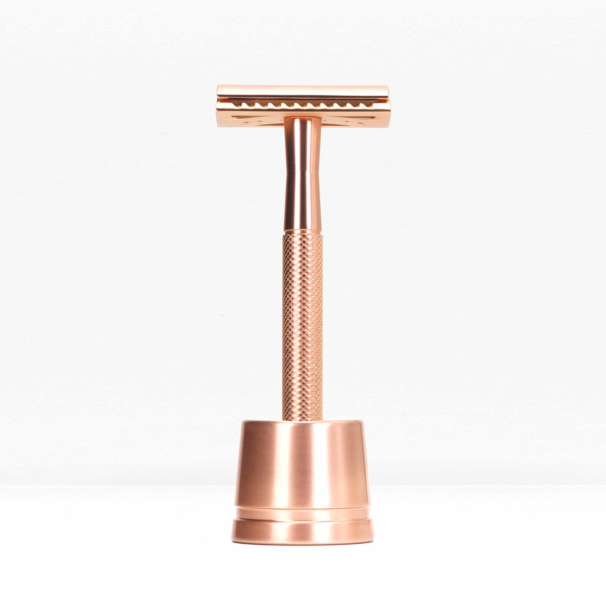 Rose gold metal double edge razor with stand photographed from the front against a white backdrop