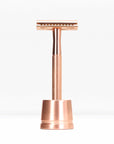 Rose gold metal double edge razor with stand photographed from the front against a white backdrop