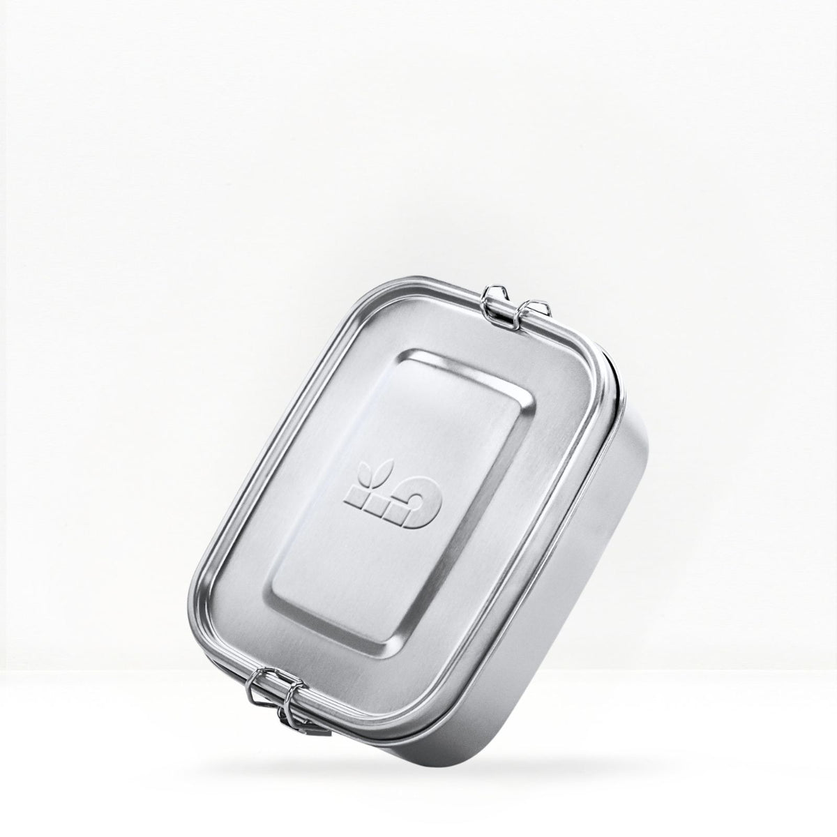 Close up of a stainless steel lunch box lid with a metal clasp against a light background