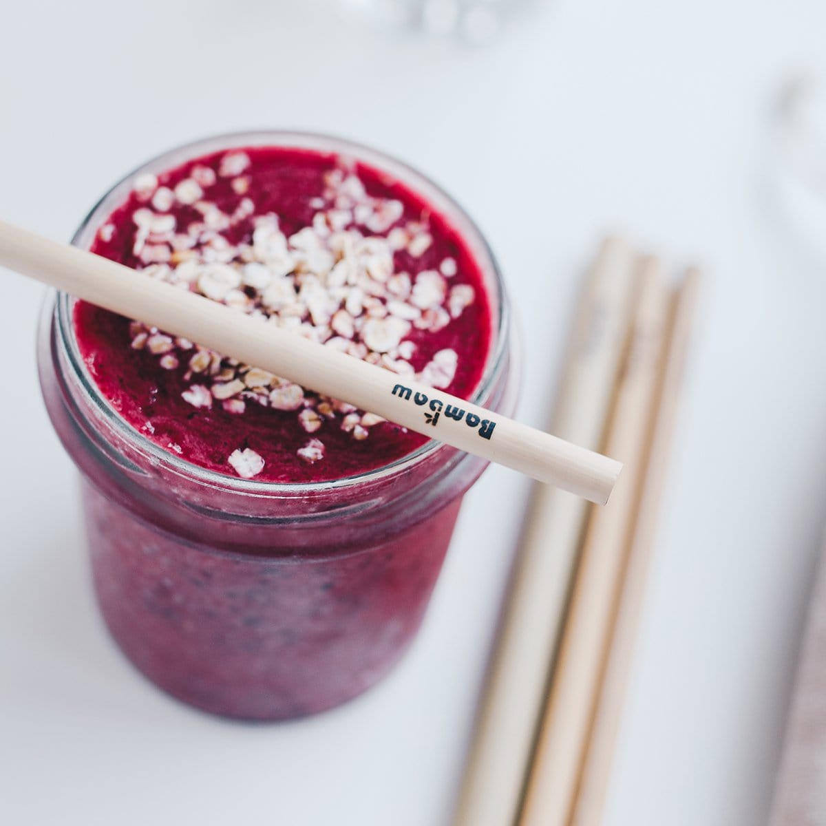 Purple smoothie in a jar with a bamboo straw across the rim