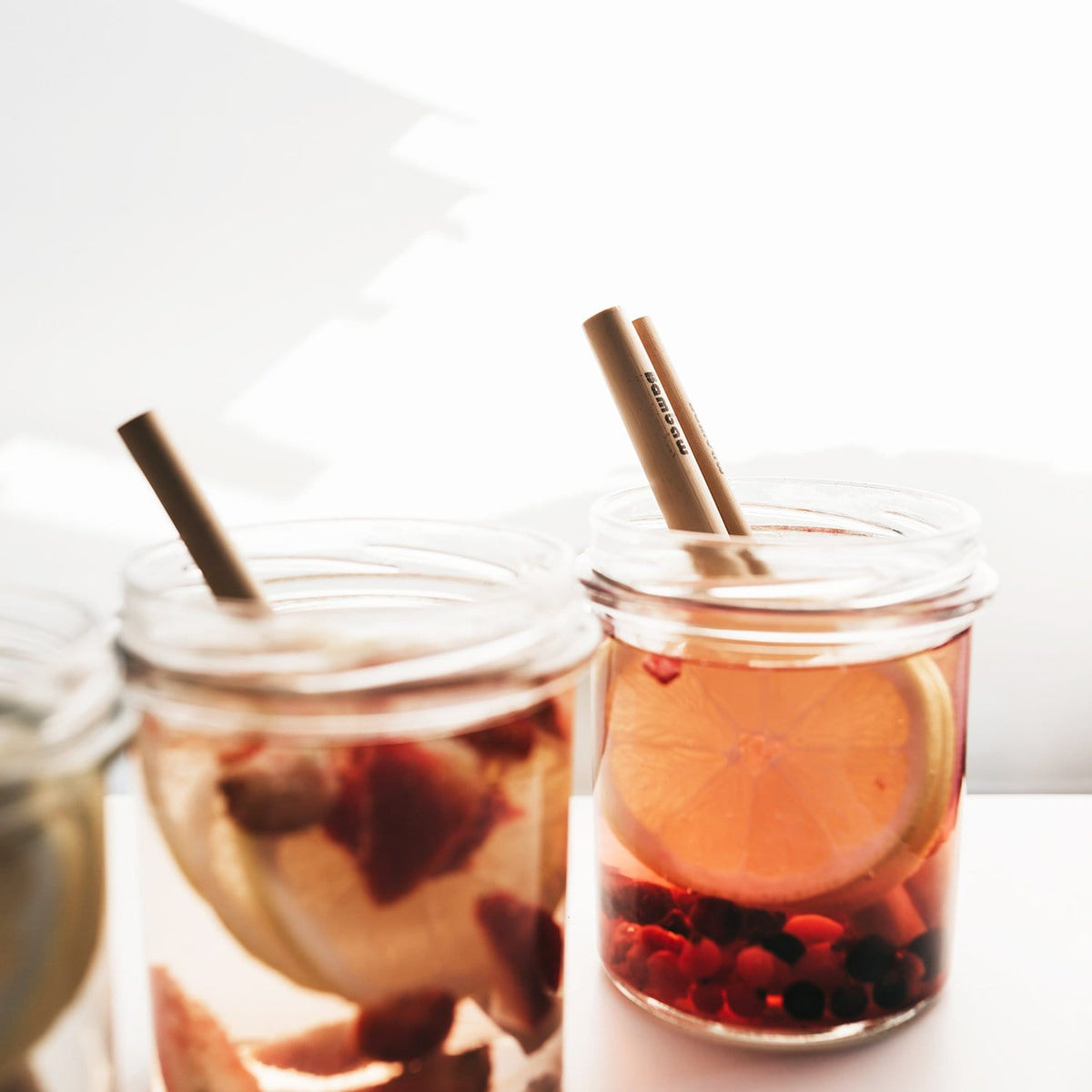 Bamboo straws placed in two jars of fruity drinks