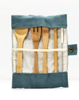 Top view of a bamboo cutlery set tucked into a blue denim roll with wooden utensils peeking out.