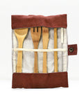 Open teal bamboo cutlery roll revealing spoon fork knife and serrated blade arranged in fabric pockets