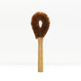Brown fluffy dish brush with wooden handle on a white background