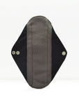 Close-up of a grey fabric reusable sanitary pad with black wings on a white background