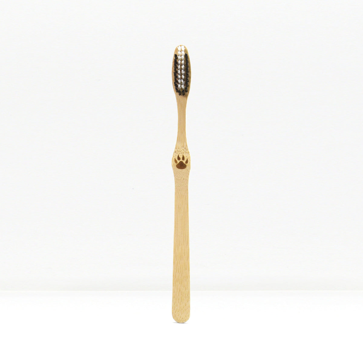 Single bamboo toothbrush standing upright against a plain white background