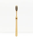 Single bamboo toothbrush standing upright against a plain white background