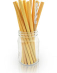Glass jar filled with light brown bamboo drinking straws and a metal cleaning brush against a white background