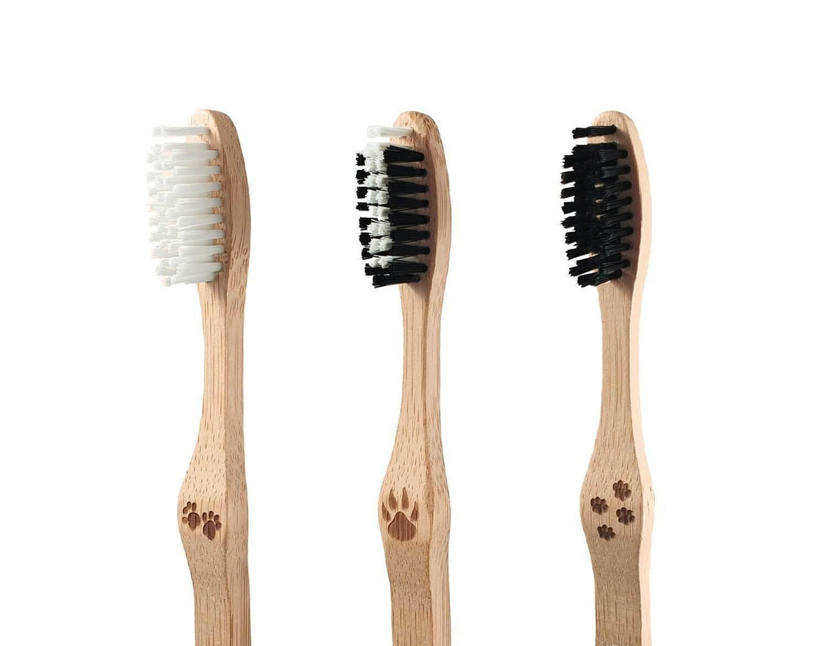 Three bamboo toothbrushes with white and black bristles arranged in a row
