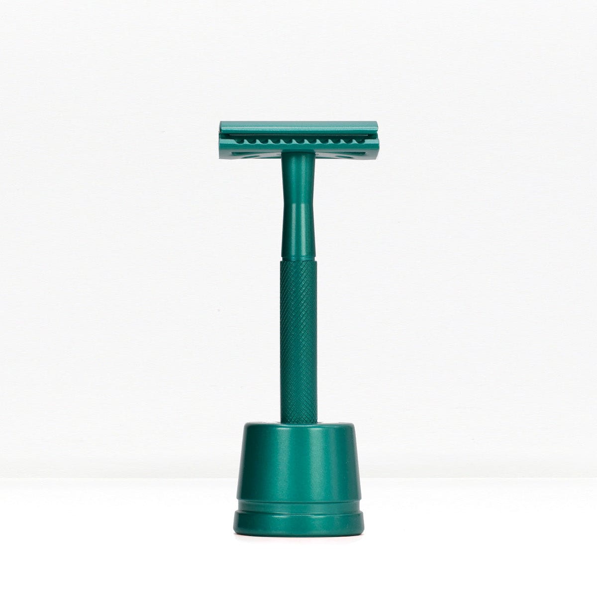 Teal metal double edge razor on a teal stand against a white background