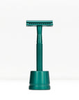Teal metal double edge razor on a teal stand against a white background