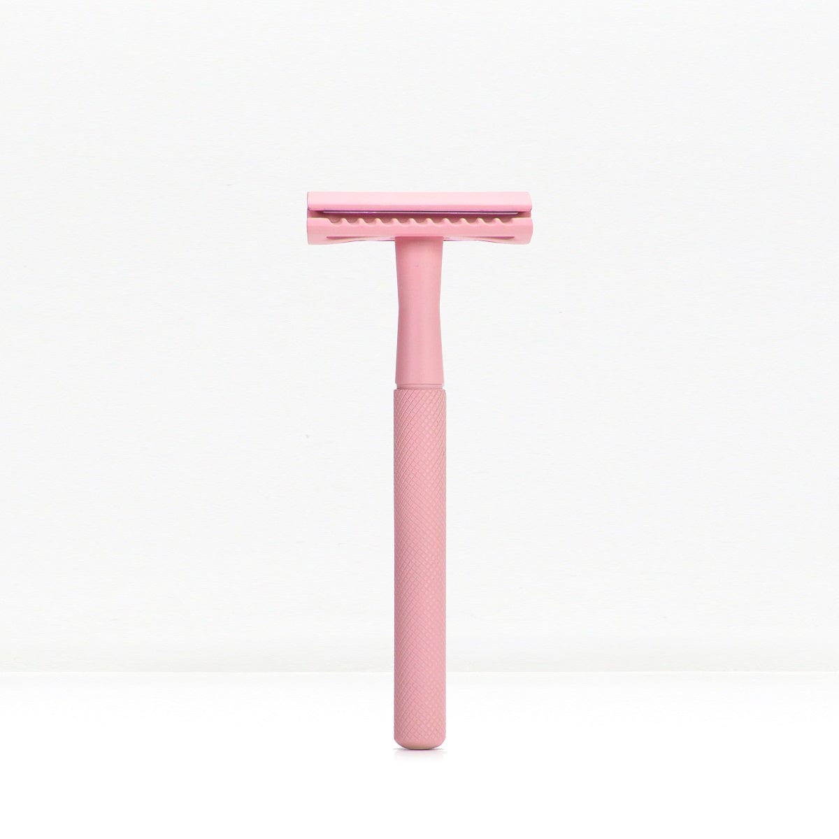 Pink metal double edge safety razor with textured handle against a white background