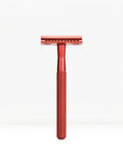 Red metal double edge safety razor with a knurled handle standing upright