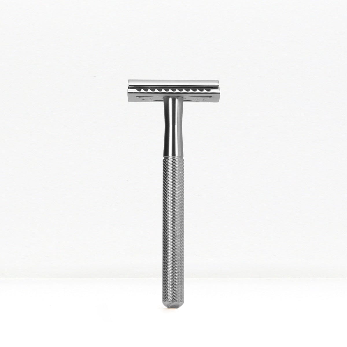 Chrome finished double edge safety razor with knurled handle standing upright.