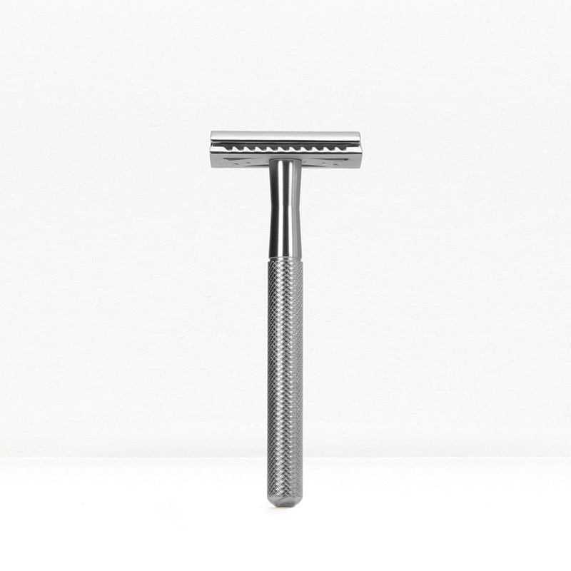 Chrome finished double edge safety razor with knurled handle standing upright.