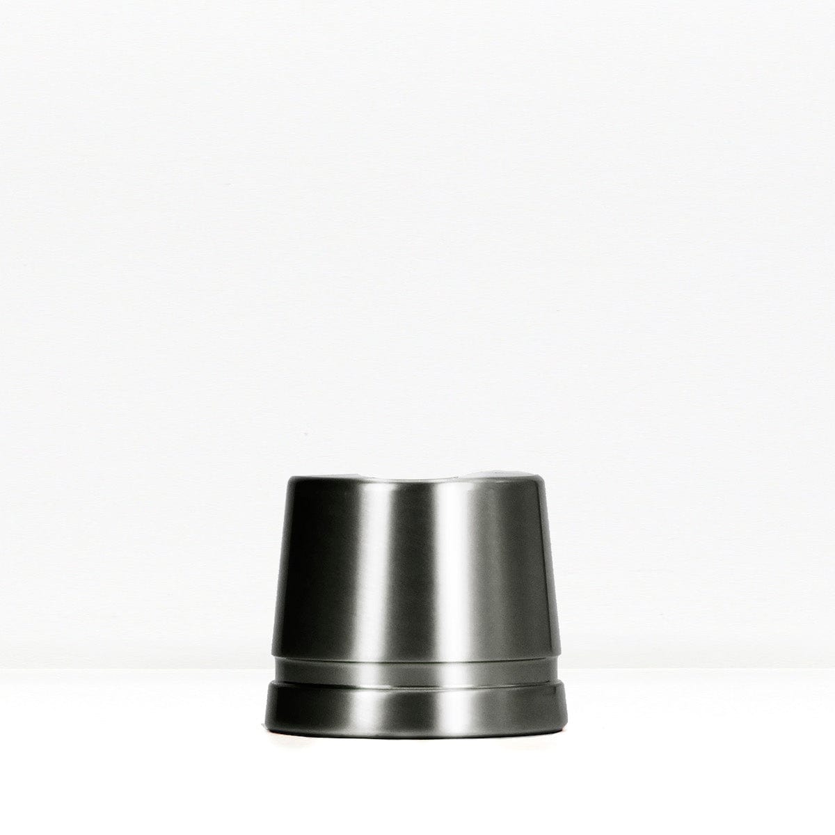 Dark gunmetal safety razor stand on a white surface.