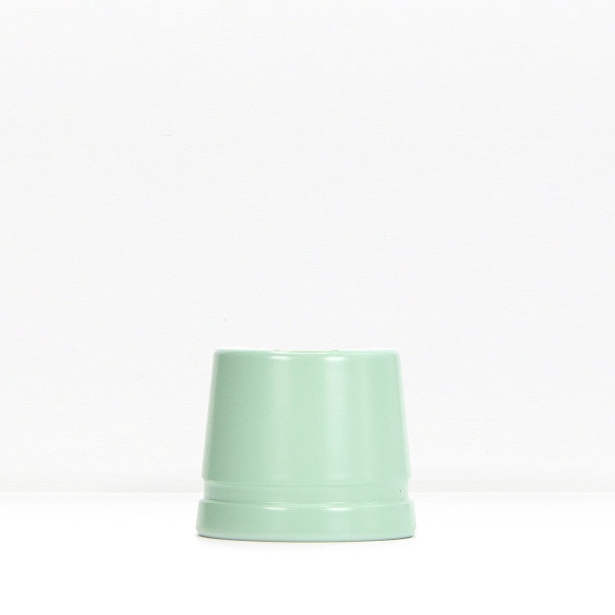 Mint green metal safety razor stand resting on a white surface
