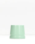 Mint green metal safety razor stand resting on a white surface