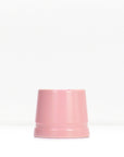 Soft pink metal safety razor stand resting on a white surface