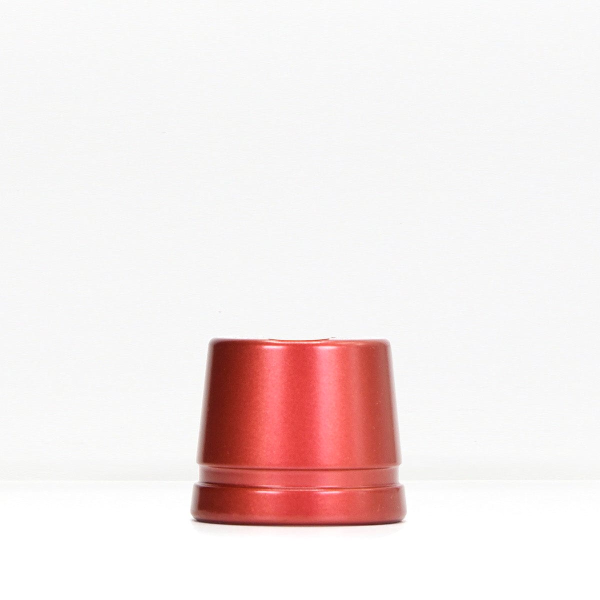 Red metal safety razor stand resting on a white surface