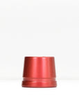 Red metal safety razor stand resting on a white surface