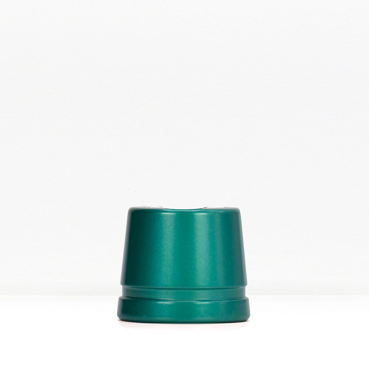 Teal metal safety razor stand on a white surface.