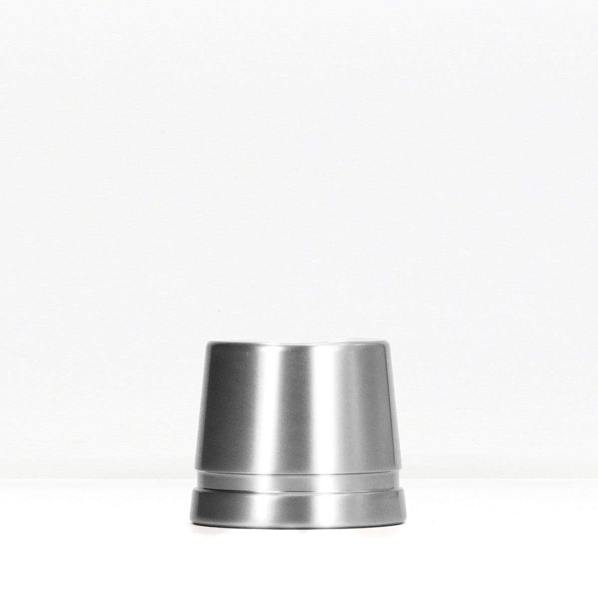 Polished silver metal safety razor stand on a white surface.