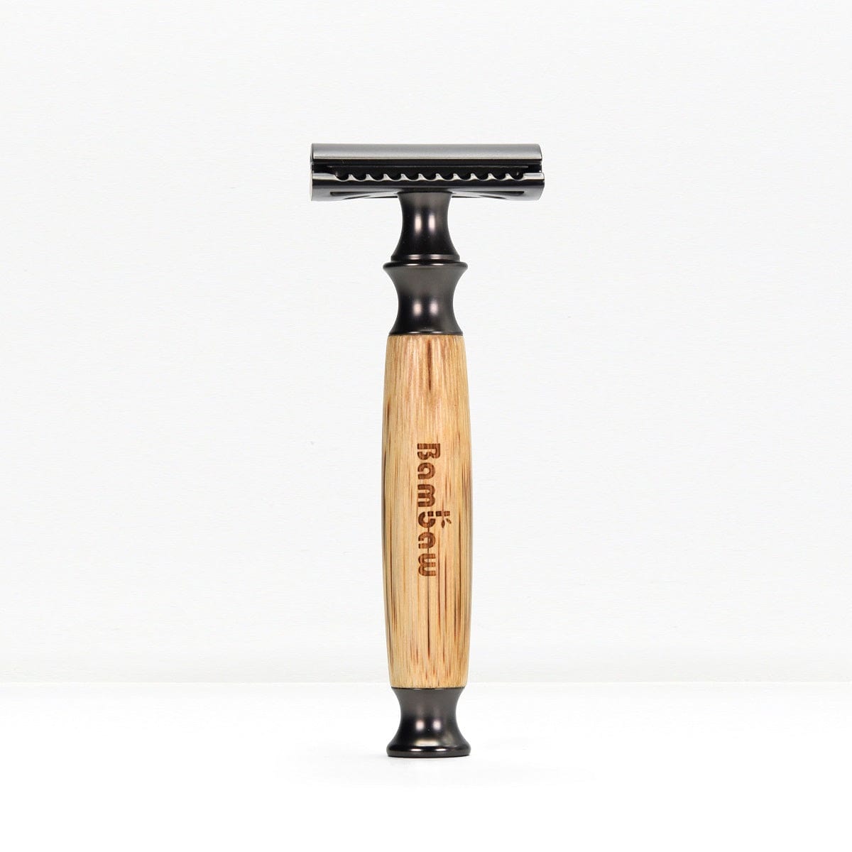 Bamboo safety razor with light bamboo handle and matte black head standing upright on a white background