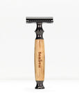 Bamboo safety razor with light bamboo handle and matte black head standing upright on a white background