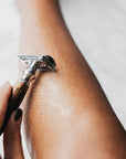 Close up of a bamboo safety razor gliding over a forearm with shaving foam.