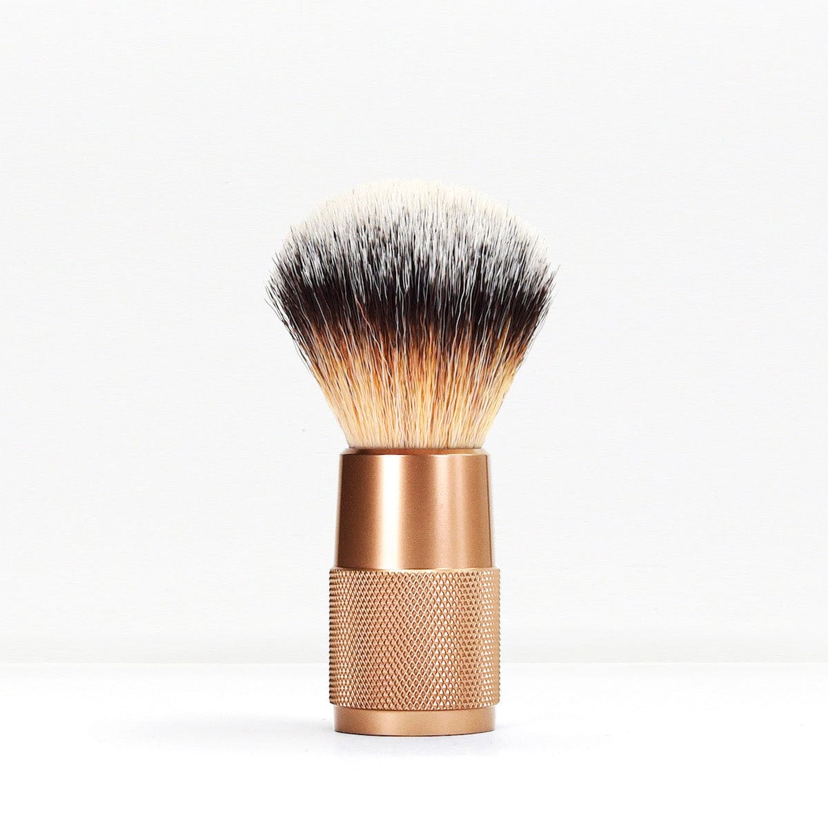 Shaving brush with cream bristles fading to black and a copper knurled metal handle