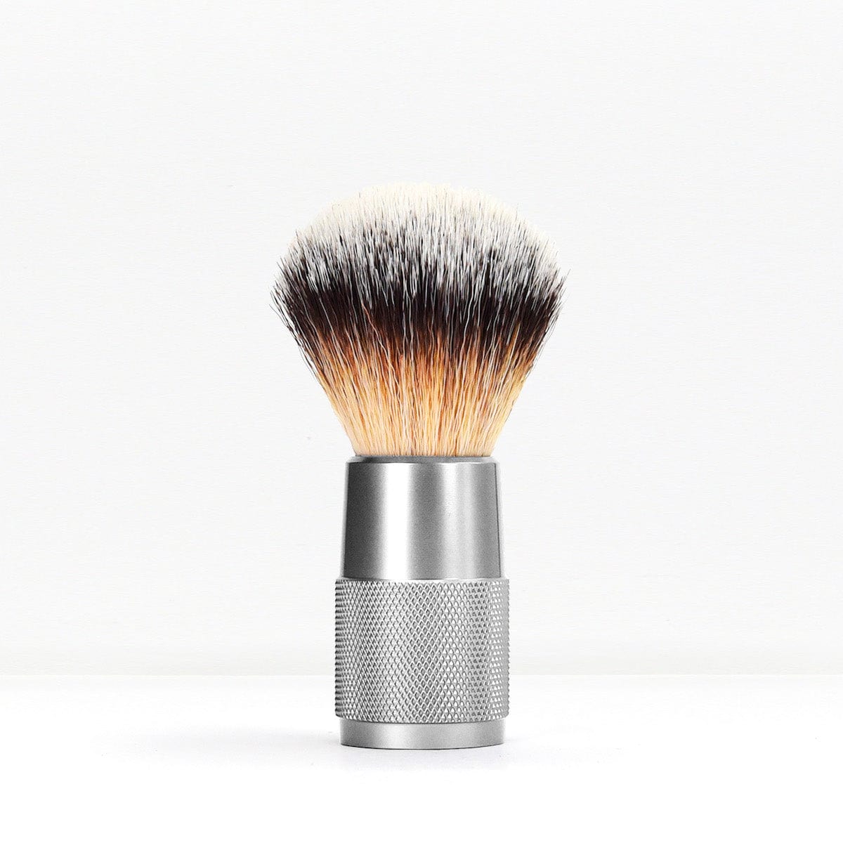 Shaving brush with a silver metal handle and knurled grip against a white background