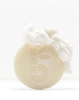 Close-up of a pale shaving bar with rough white chunks on top against a white backdrop