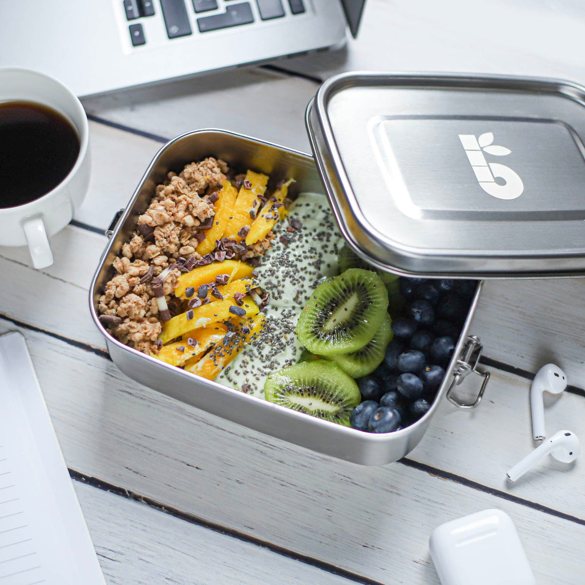 Stainless steel leakproof lunch box opened to show a meal with mango kiwi and granola